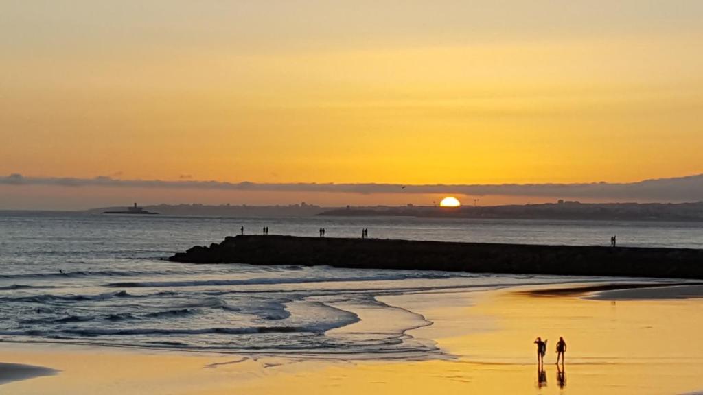 due persone che camminano sulla spiaggia al tramonto di The View - Sea, Surf and Lisbon a Costa da Caparica
