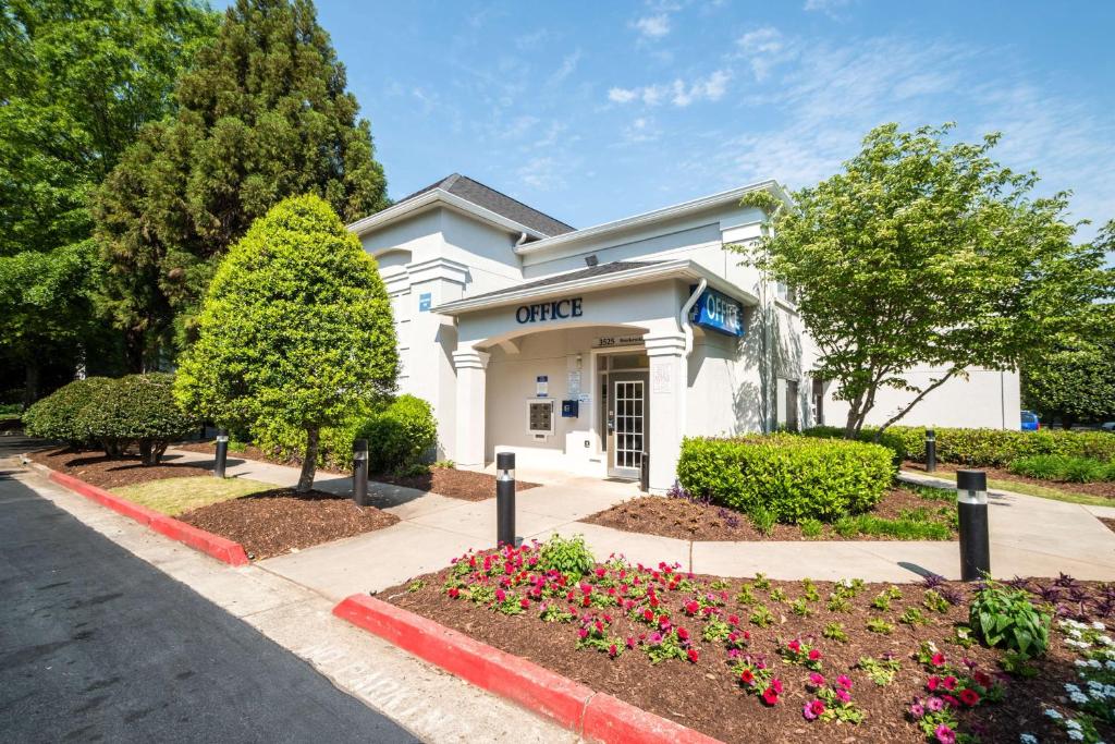 a white building with flowers in front of it at Studio 6-Duluth, GA - Atlanta - Gwinnett Place in Duluth