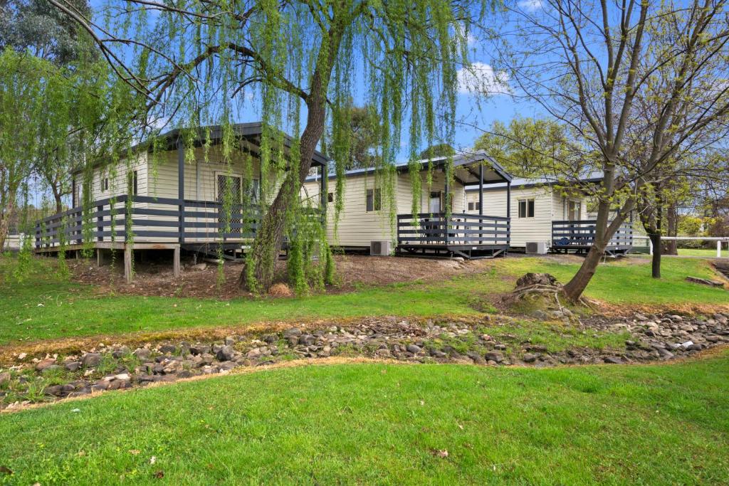 a white house with a tree in the yard at High Country Holiday Park in Mansfield