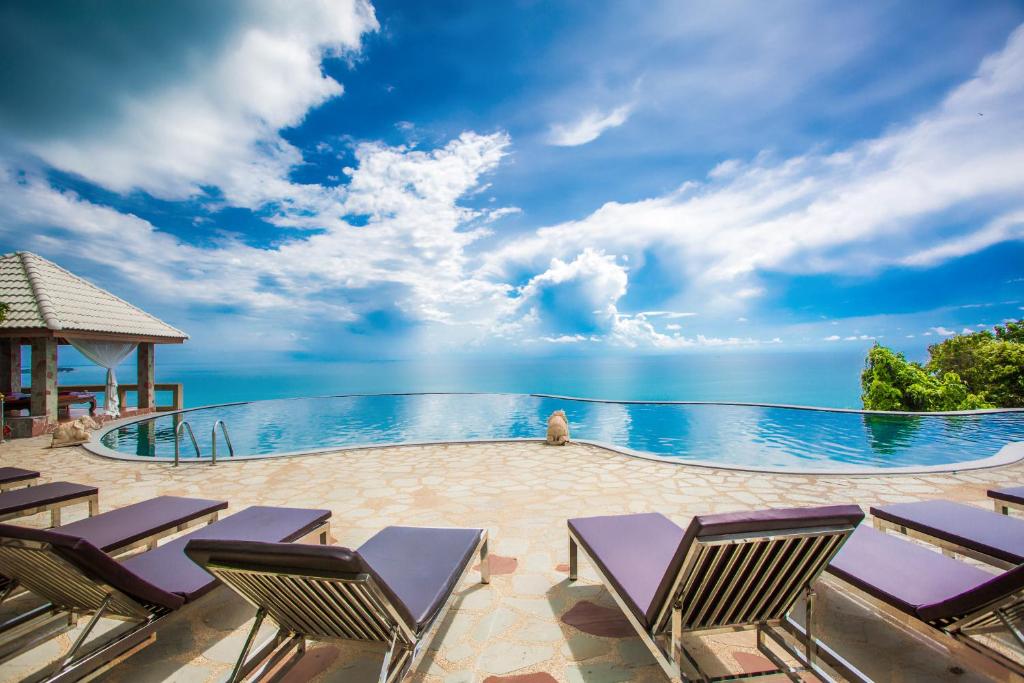 einen Pool mit Stühlen und das Meer im Hintergrund in der Unterkunft Samui Bayview Resort & Spa - SHA Plus in Strand Chaweng Noi