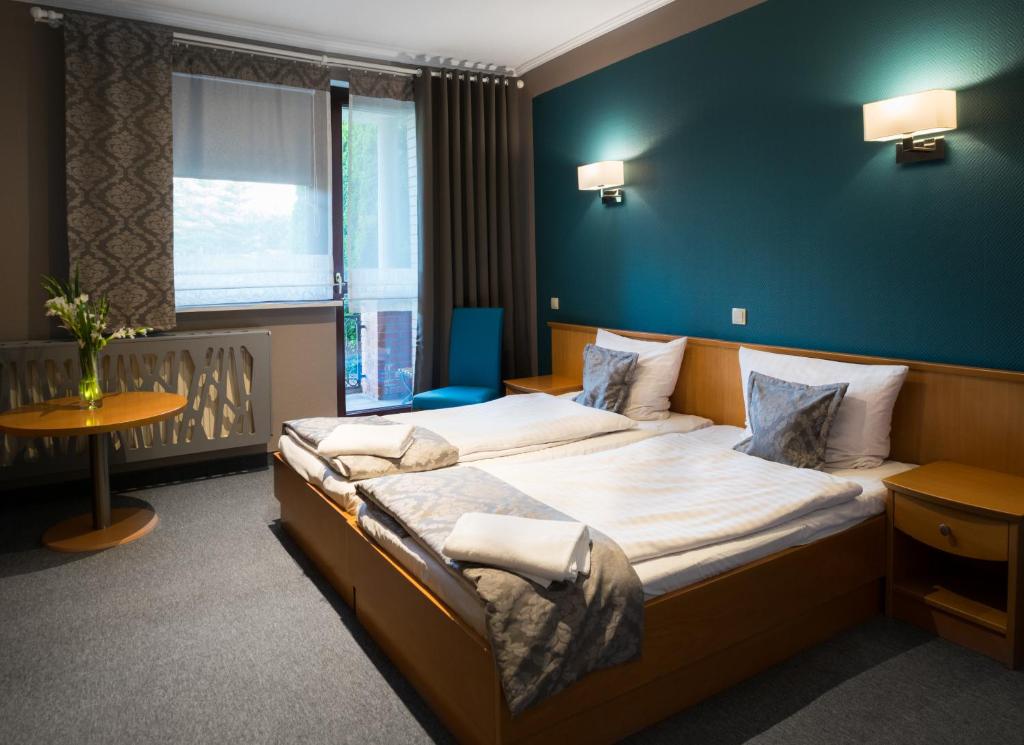 1 dormitorio con 1 cama grande y pared azul en Hotel Restauracja Tawerna Gliwice, en Gliwice