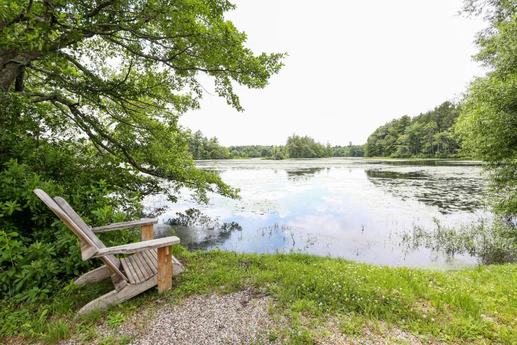 a wooden bench sitting next to a lake at Tuxbury Pond Camping Resort Tiny House Murphy in South Hampton