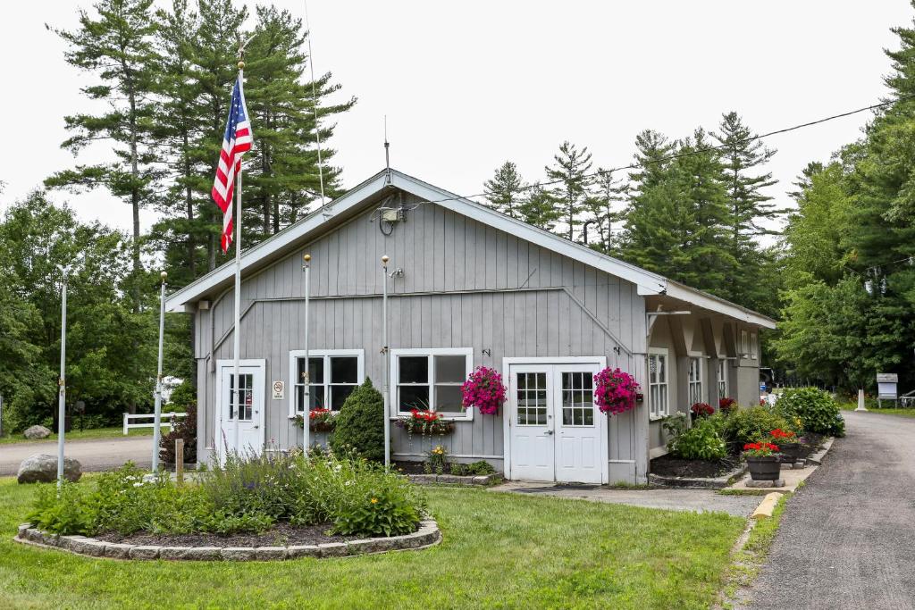 a house with an american flag in front of it at Tuxbury Pond Camping Resort Tiny House Clara in South Hampton