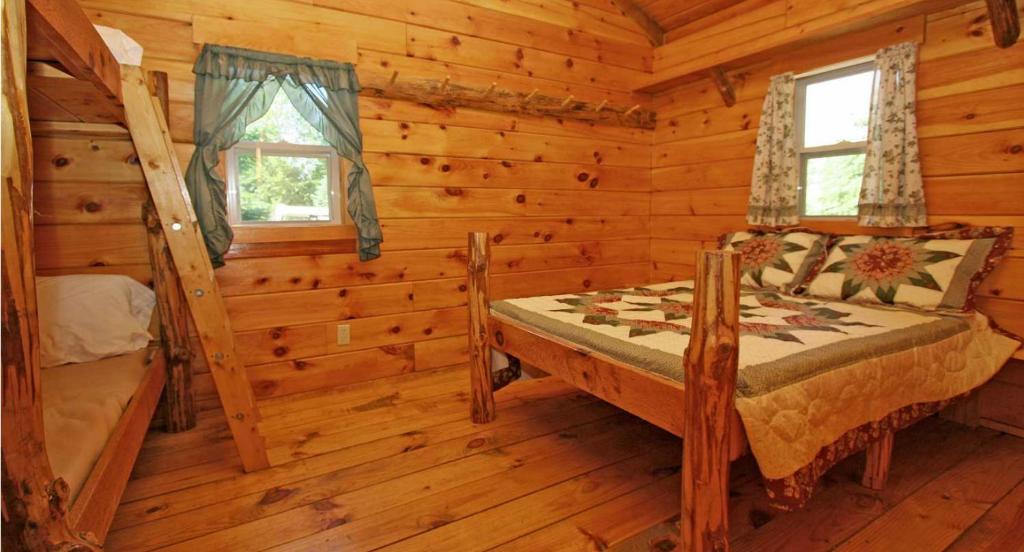 a bedroom in a log cabin with a bed and a window at Robin Hill Camping Resort Deluxe Cottage 13 in Lenhartsville