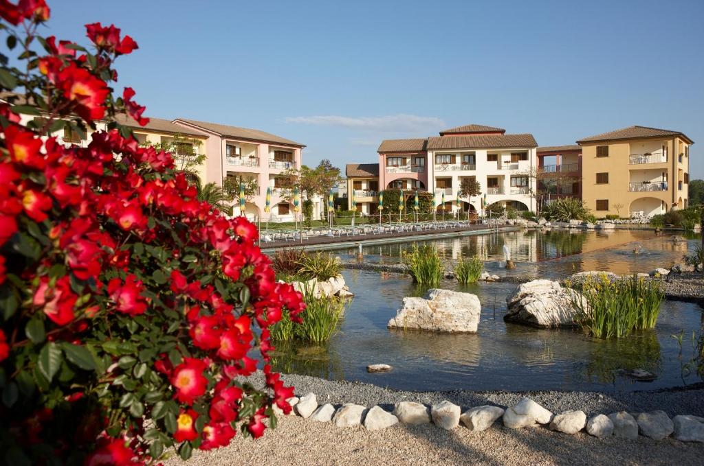 a river with rocks and red flowers in front of buildings at Hapimag Resort Scerne di Pineto in Scerne