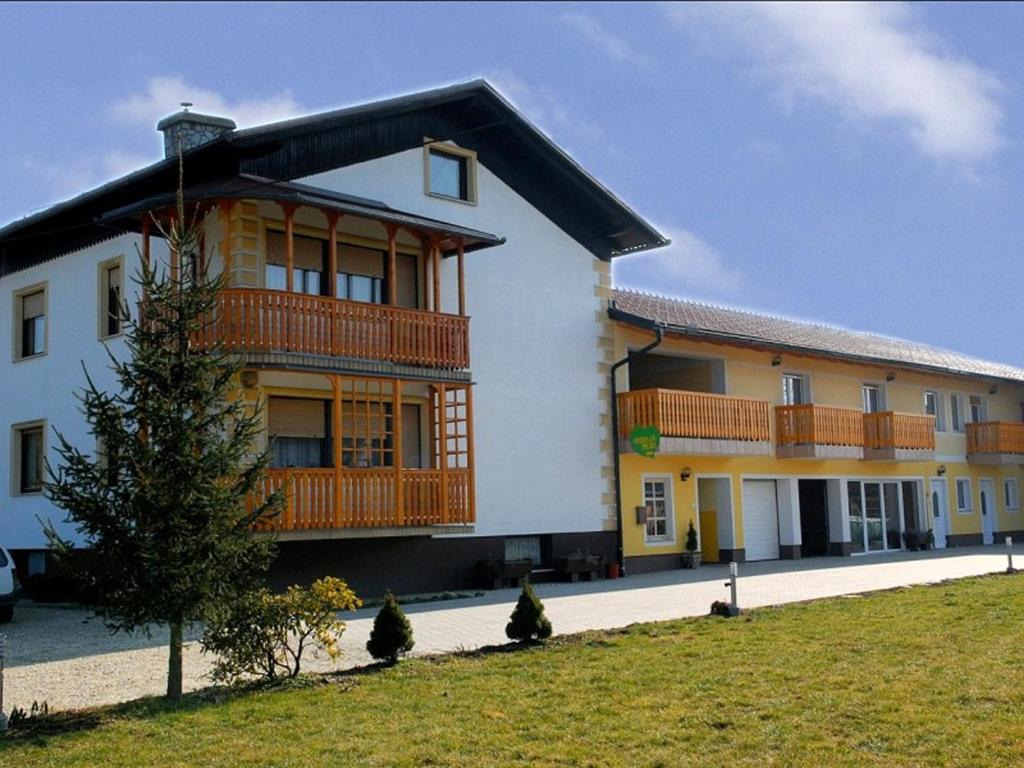 um grande edifício branco com varandas de madeira em Tourist Farm Šalamun em Banovci