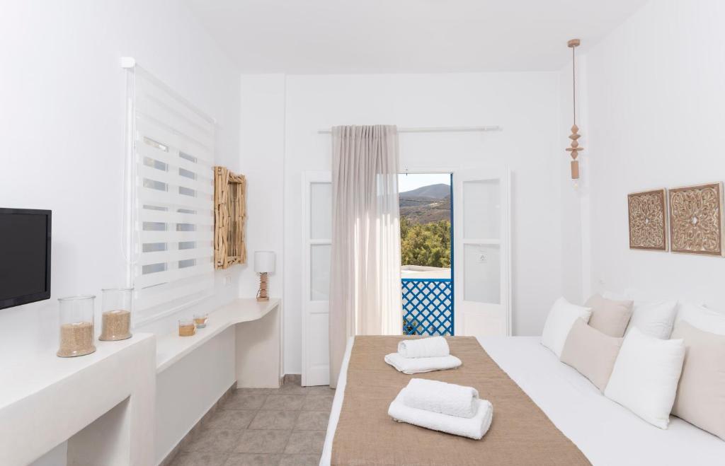 a white living room with a couch and a table at Mouras studios in Livadi Astypalaias