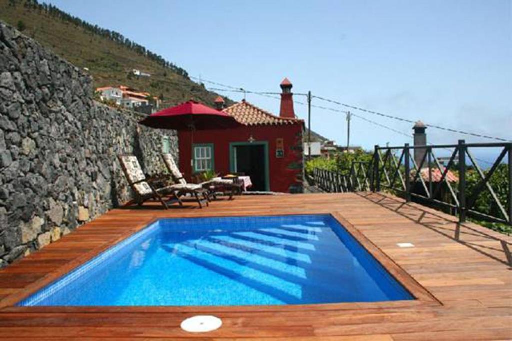 a swimming pool on a wooden deck with a house at Casa Rural La Caldera in Fuencaliente de la Palma