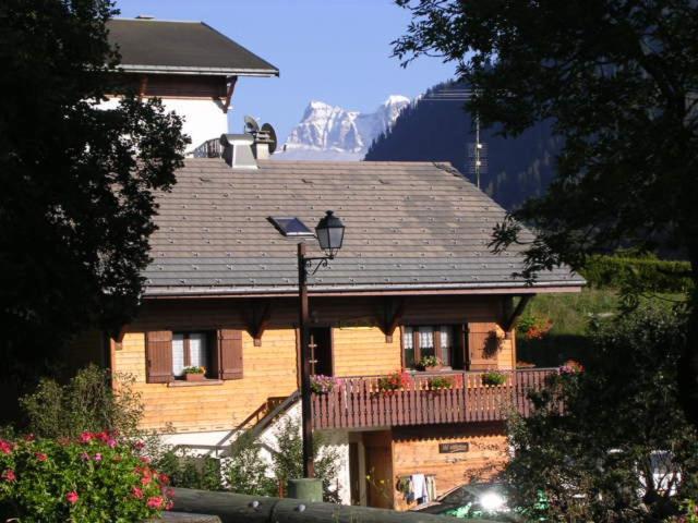 uma grande casa de madeira com uma varanda e uma montanha em Chalet Peloton em La Chapelle-dʼAbondance