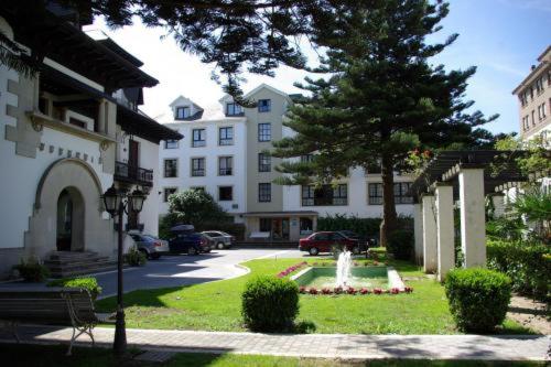 ein Gebäude mit einem Brunnen in der Mitte eines Gartens in der Unterkunft Hotel y Apartamentos Arias in Navia
