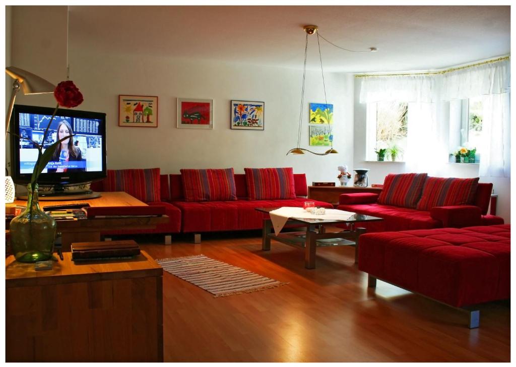 a living room with red couches and a tv at Lissi Apartment nur 5 Min vom Europa Park und direkt am Naturschutzgebiet in Kappel-Grafenhausen