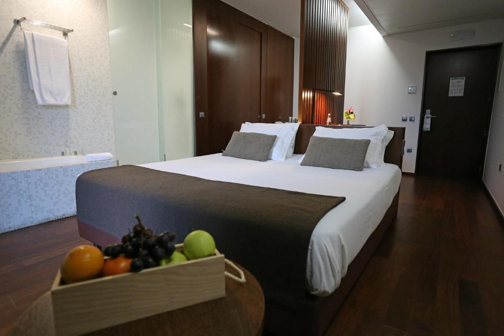 un grande letto in una camera d'albergo con un cesto di frutta di Douro Scala a Mesão Frio