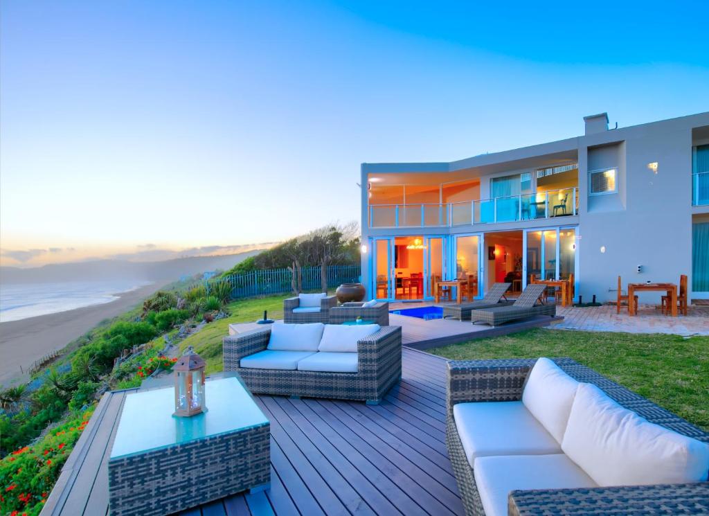 a house with a deck with furniture and the beach at Dune Villa Wilderness in Wilderness