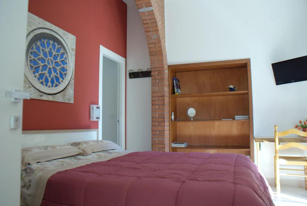a bedroom with a bed with a red wall at Appartamento Astrea in Syracuse