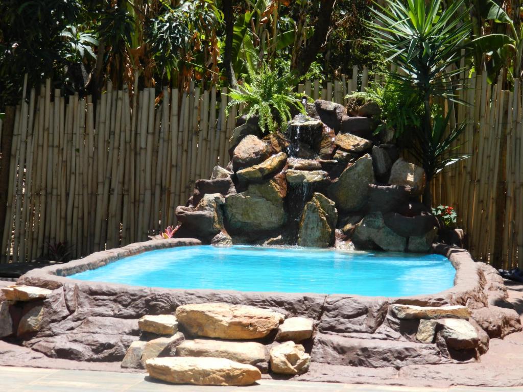 a swimming pool with a waterfall in a garden at Hospedaria Raízes da Serra in Serra do Cipo