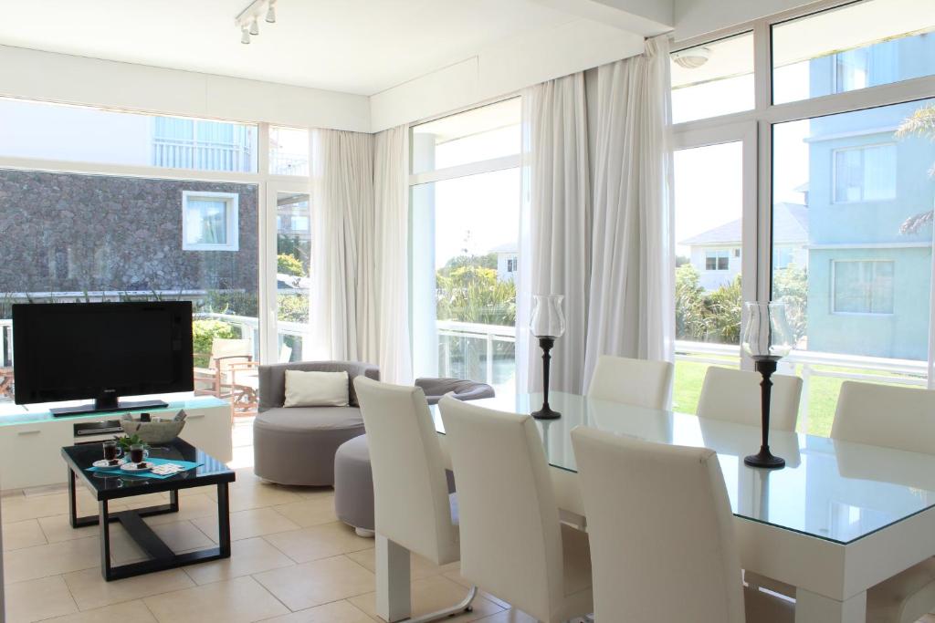 ein Wohnzimmer mit einem Tisch, Stühlen und einem TV in der Unterkunft Apartamento Playas Carilo in Carilo