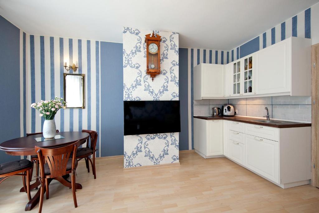 a kitchen with white cabinets and a table and a clock at Elite Apartments Ogarna Deluxe Old Town in Gdańsk