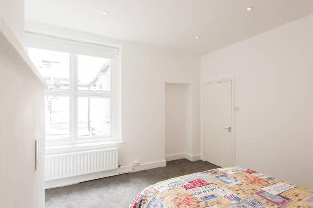 ein weißes Schlafzimmer mit einem Bett und einem Fenster in der Unterkunft Kennington Apartment 1/Apartment in London