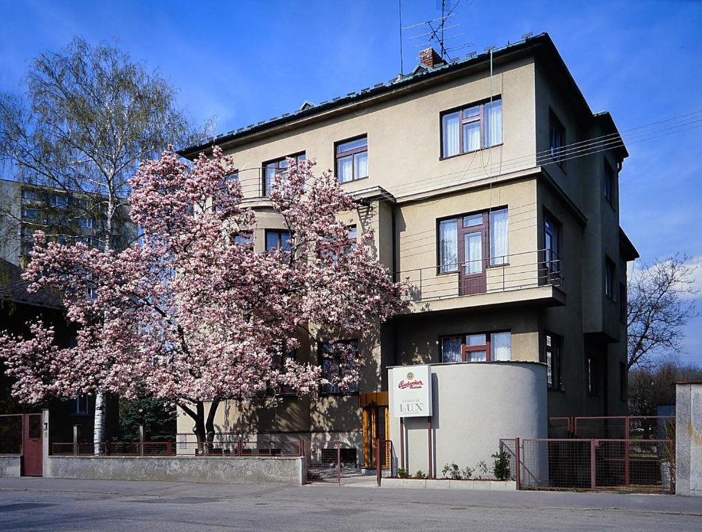 a building with a flowering tree in front of it at Hotel Lux in České Budějovice