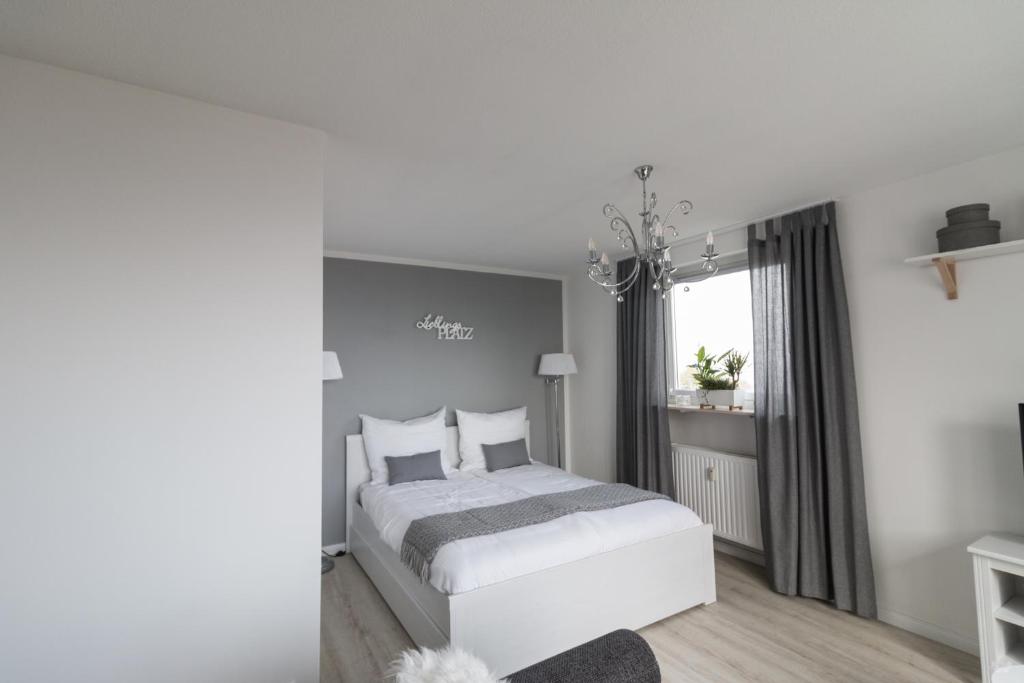 a white bedroom with a bed and a window at Ansbachs City Apartment in Ansbach
