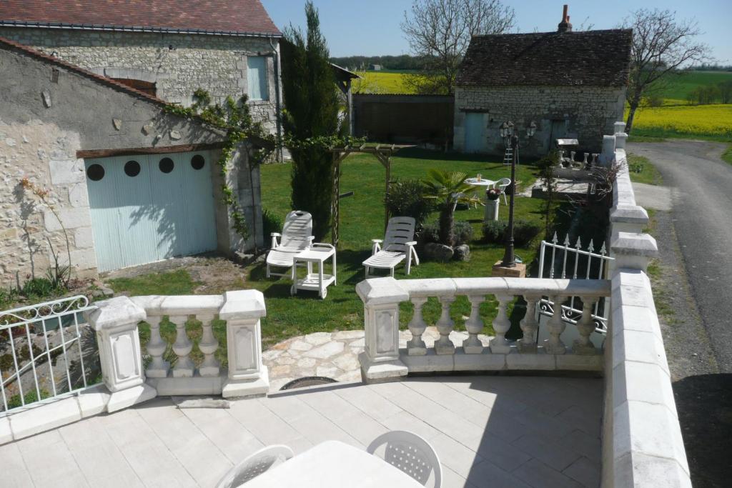 a balcony with a white railing and chairs in a yard at Aux Jardin&#39;s de la Bosniere in Cussay