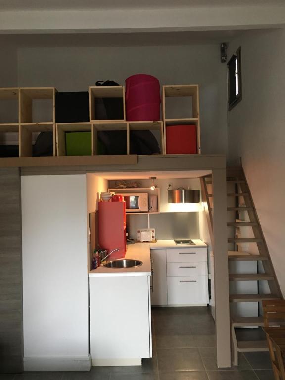 a small kitchen with white cabinets and a staircase at Gruissan Studio in Gruissan