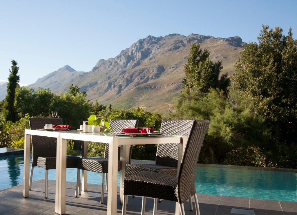 een witte tafel en stoelen op een patio naast een zwembad bij Keren's Vine Guesthouse in Stellenbosch