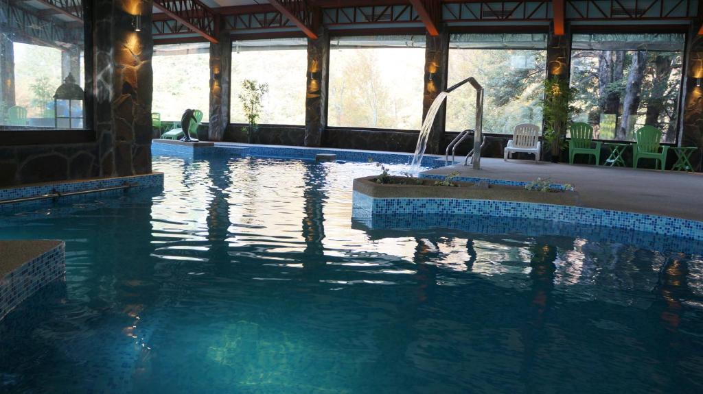 una piscina con una fuente en un edificio en Cabañas Blanche Neige Wellness & SPA en Las Trancas