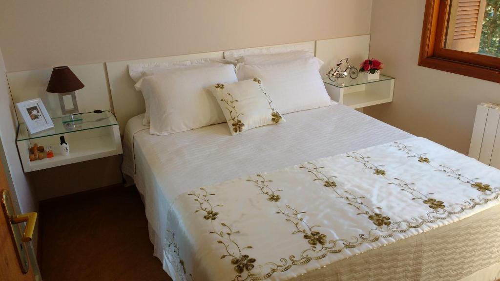 1 dormitorio con 1 cama blanca con sábanas y almohadas blancas en Apartamento Flat, en Gramado