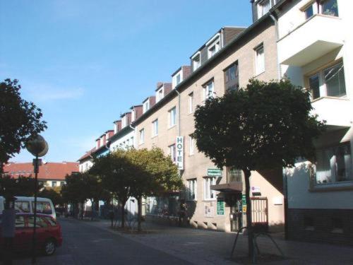 uma rua da cidade com um edifício e árvores em frente em Altstadthotel Wienecke em Braunschweig
