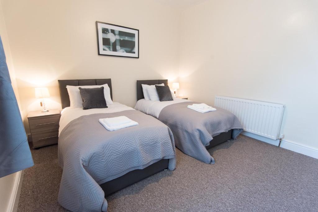two beds in a room with two lamps on at Campbell House in Gainsborough