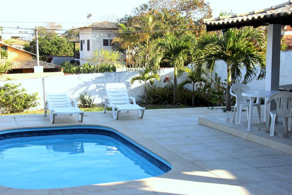 een patio met een zwembad en stoelen en een tafel bij Casa Sitio Região dos Lagos 1200m2 terreno- S Pedro DAldeia in São Pedro da Aldeia