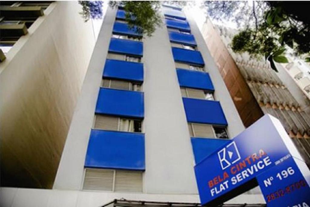 un edificio con ventanas azules y una señal delante de él en Bela Cintra Flat Service, en São Paulo