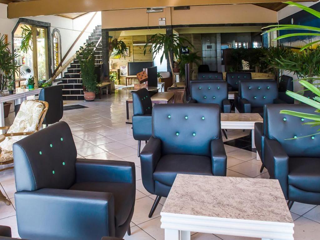 un restaurante con sillas azules, mesas y escaleras en Morada Manga Rosa Pousada, en Florianópolis