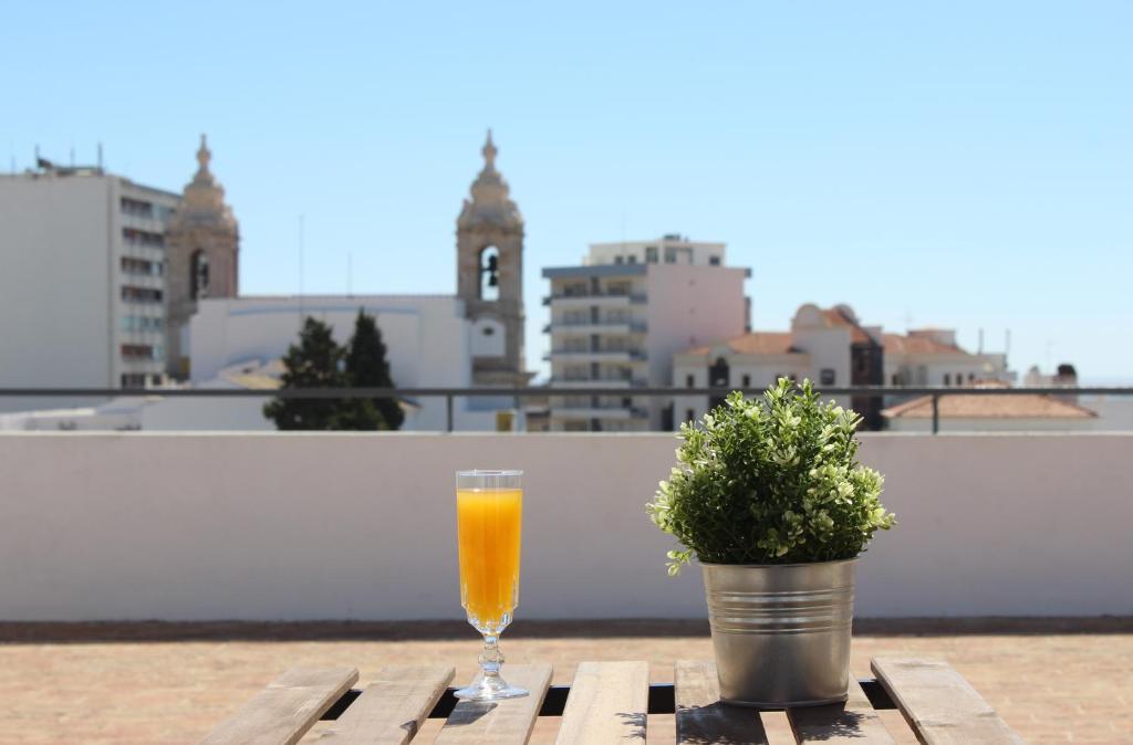 a glass of orange juice sitting on a table with a potted plant at Carmo Twenties Apartment in Faro