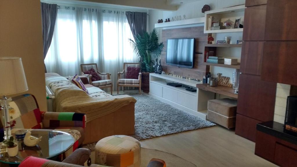 sala de estar con sofá y TV en Lindo apartamento no centro de Canela en Canela