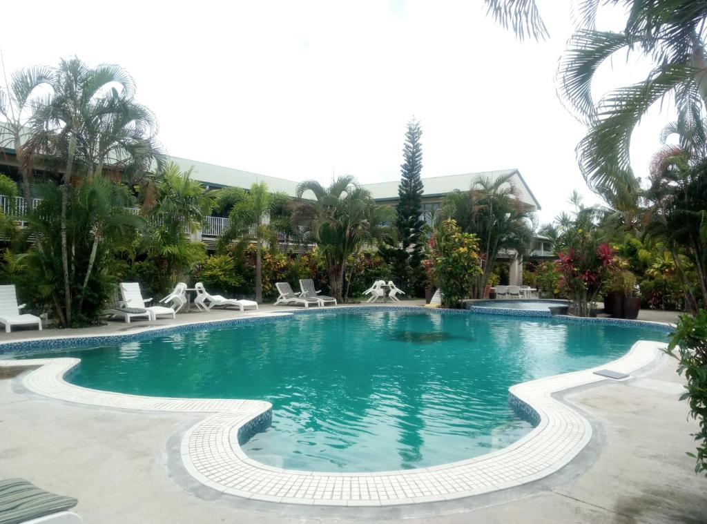 una piscina en un complejo con sillas y palmeras en Hotel Millenia Samoa en Apia