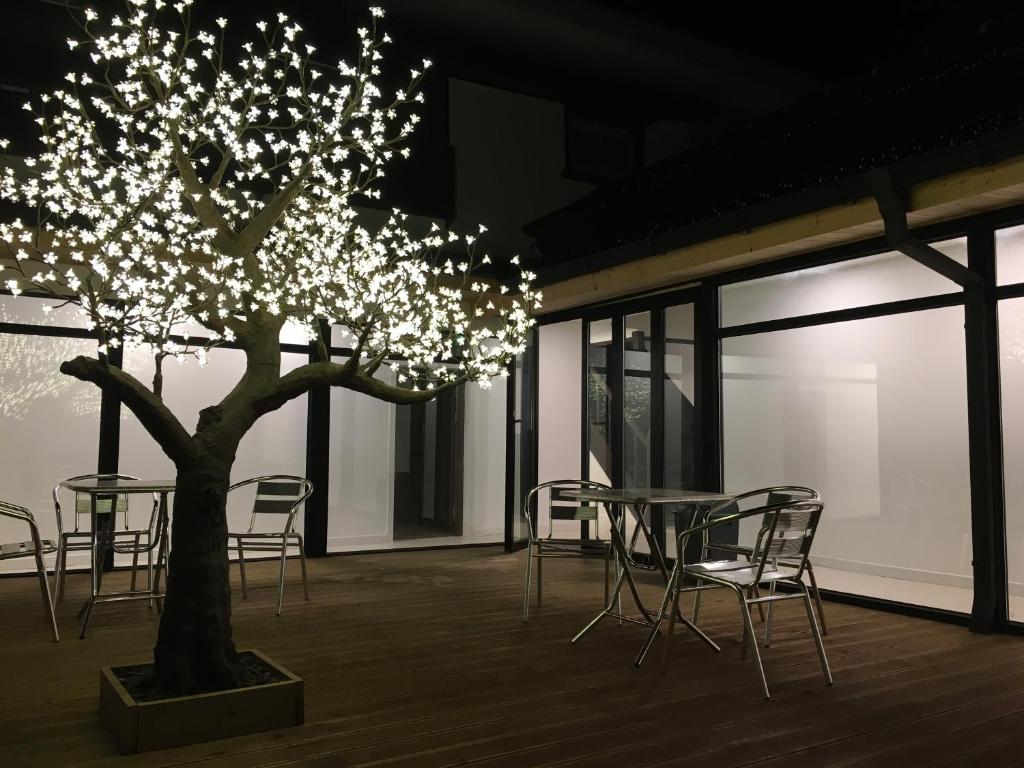 een tafel en stoelen en een boom met verlichting bij Hwadam Inn in Gunsan