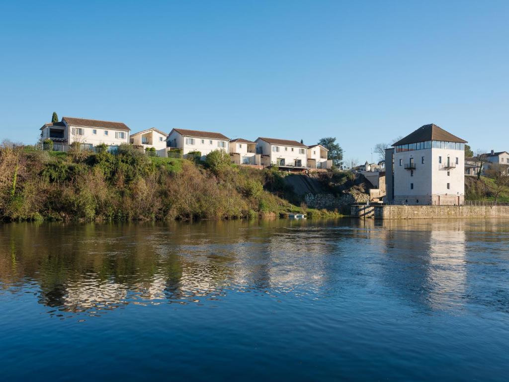 un groupe de maisons sur une colline à côté d'une rivière dans l'établissement Hôtel Mercure Villeneuve sur Lot Moulin de Madame, à Villeneuve-sur-Lot