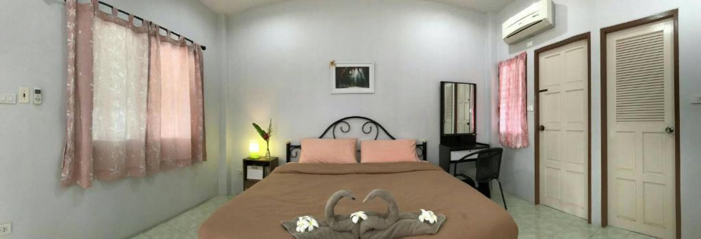 um quarto com uma cama grande e almofadas cor-de-rosa em 2N Guesthouse em Phetchaburi
