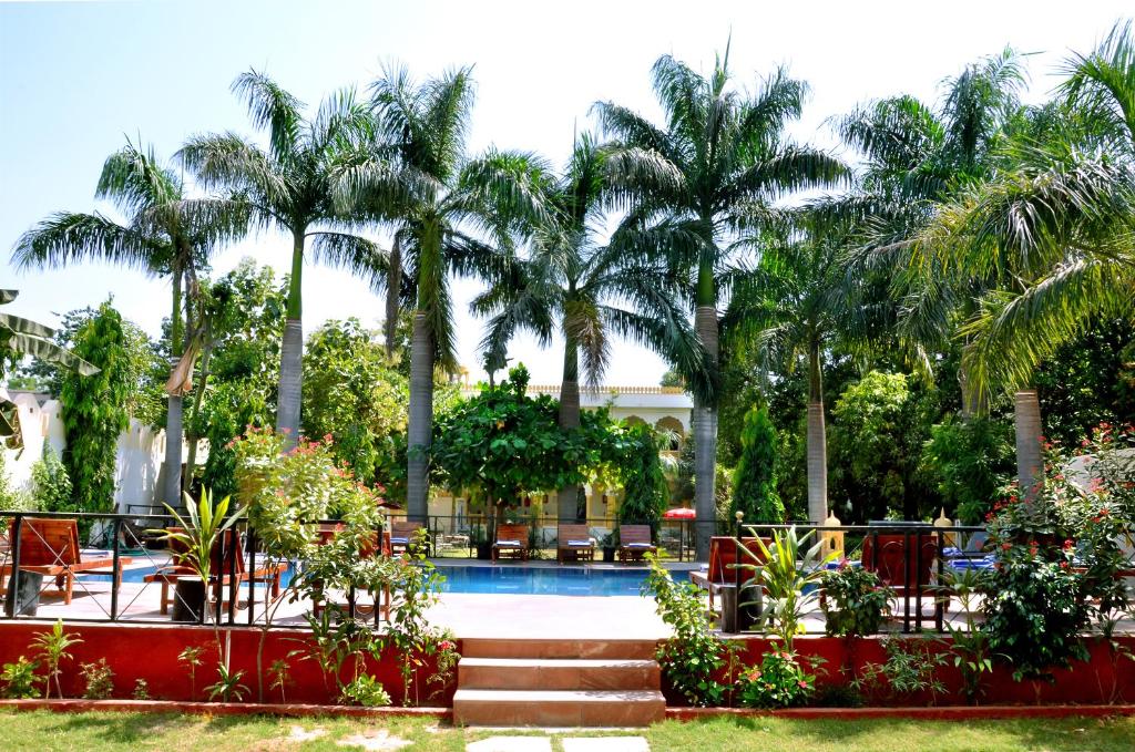 a resort with palm trees and a swimming pool at Raj Palace Resort in Sawāi Mādhopur