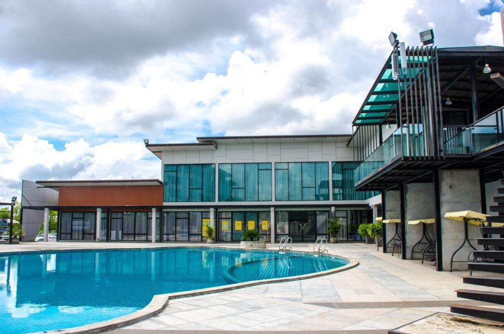 a building with a swimming pool in front of a building at Prajaktra Design Hotel in Udon Thani