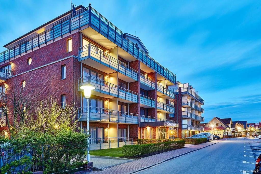 a large brick building with balconies on a street at Hotel Schelf GmbH & Co. KG in Büsum