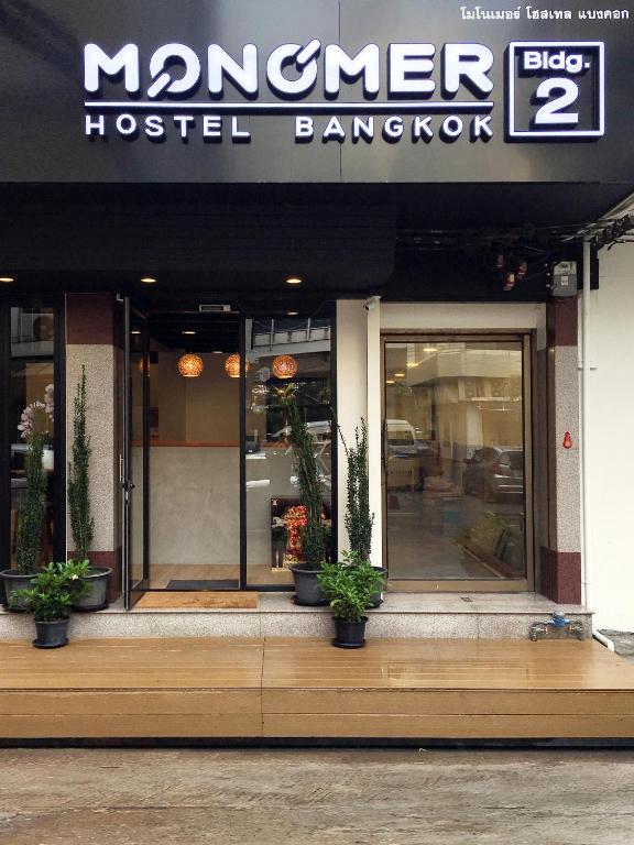 a hostel restaurant with potted plants in front of it at Monomer Hostel Bangkok in Bangkok