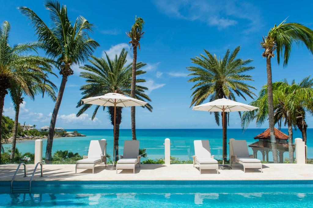 聖約翰斯的住宿－藍色海域Spa度假酒店，一个带椅子和遮阳伞的游泳池以及大海