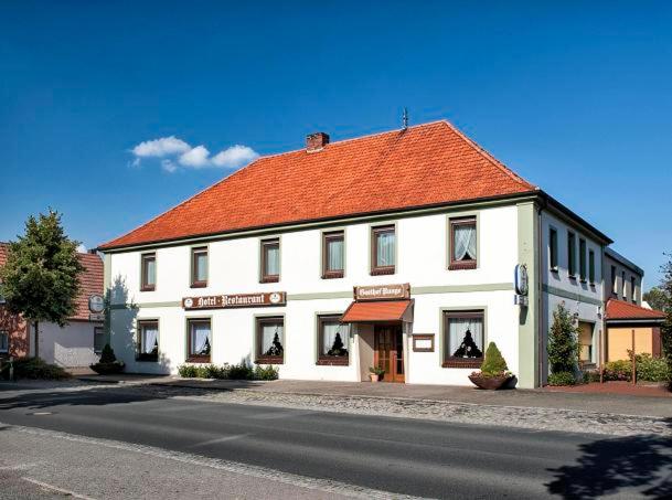 a large white building with an orange roof on a street at Gasthof Runge in Barenburg