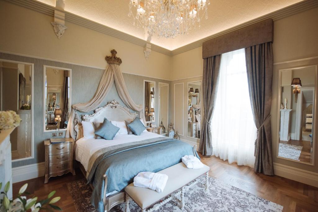 une chambre avec un grand lit et un lustre dans l'établissement Cornhill Castle, à Biggar