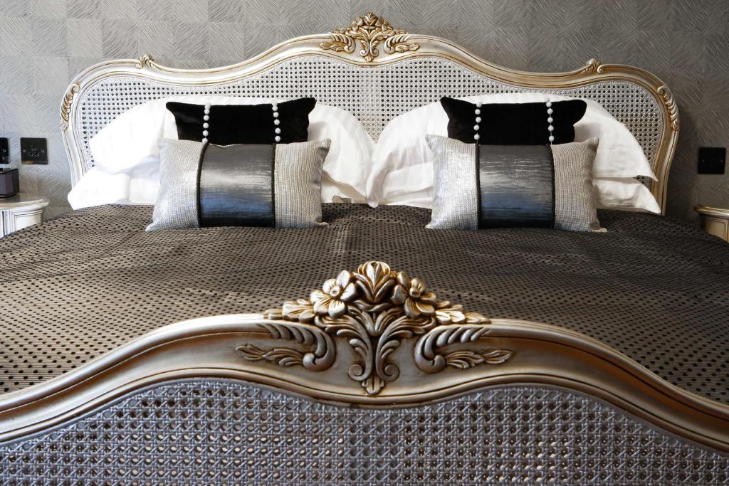 een groot bed met een gouden frame en kussens bij Windermere Suites in Windermere