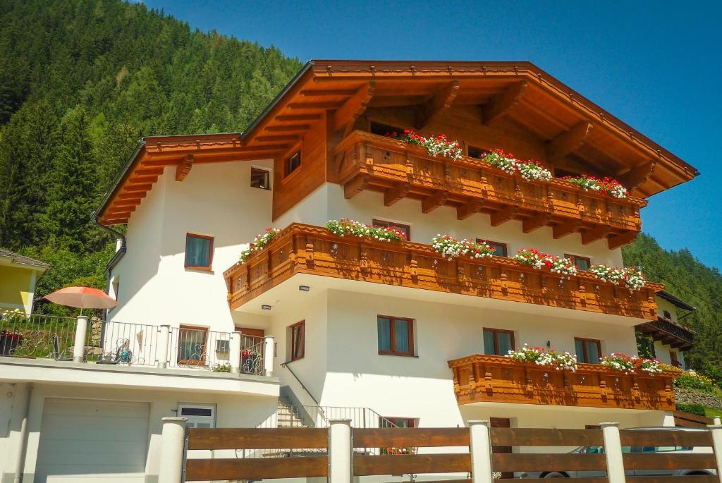 un edificio con balcones de madera y flores. en Pension am Rain, en Neustift im Stubaital