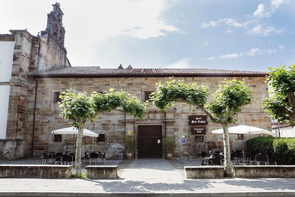 un antiguo edificio de piedra con mesas y sombrillas en Hotel Convento San Roque, en Balmaseda